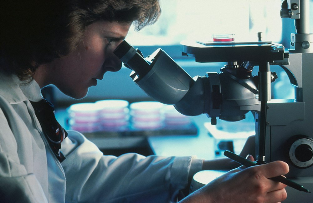 Cercetătoare la microscop, într-un laborator