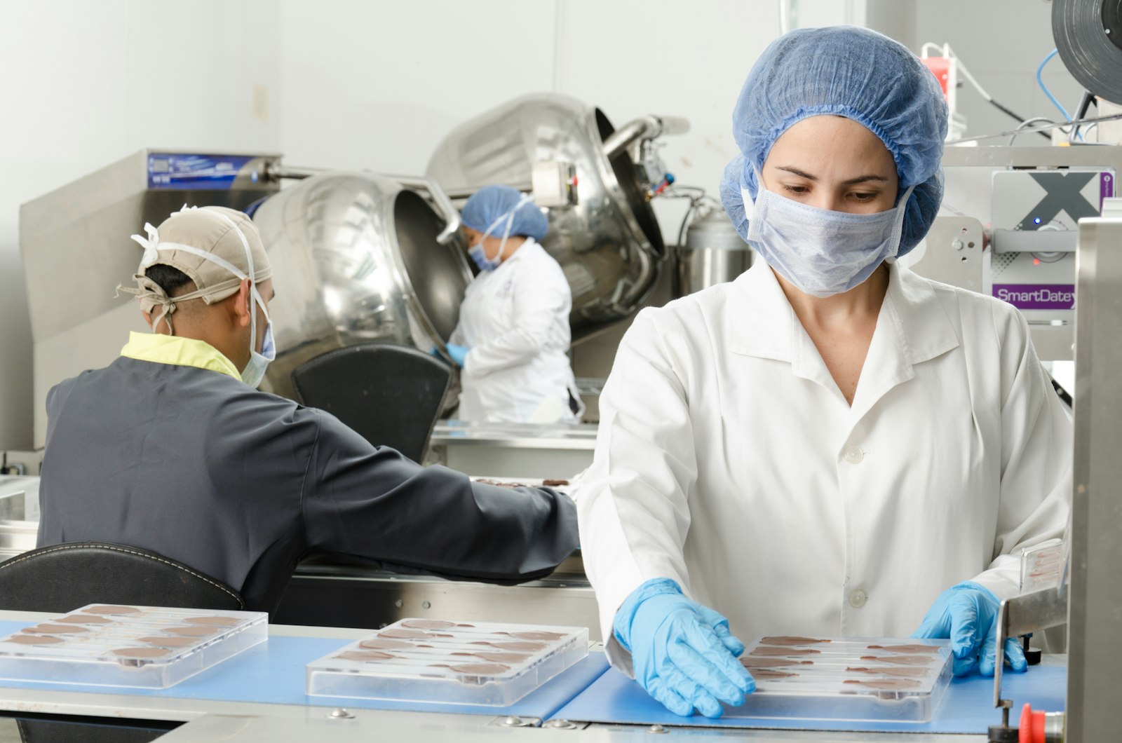 Angajate cu bonetă și mănuși pe o linie de producție alimentară